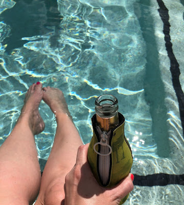 Woman with legs in pool drinking a beer on Labor Day 